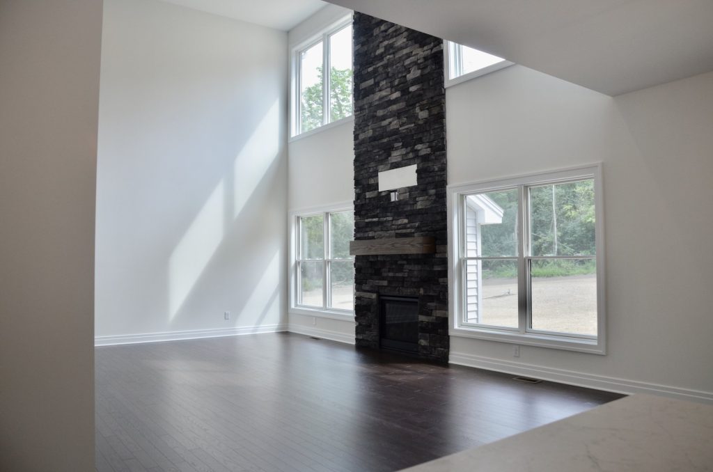 Arbordale-Two-Story-Great-Room-with-Floor-to-Ceiling-Stone-Fireplace-Large-Windows-and-Dark-Flooring