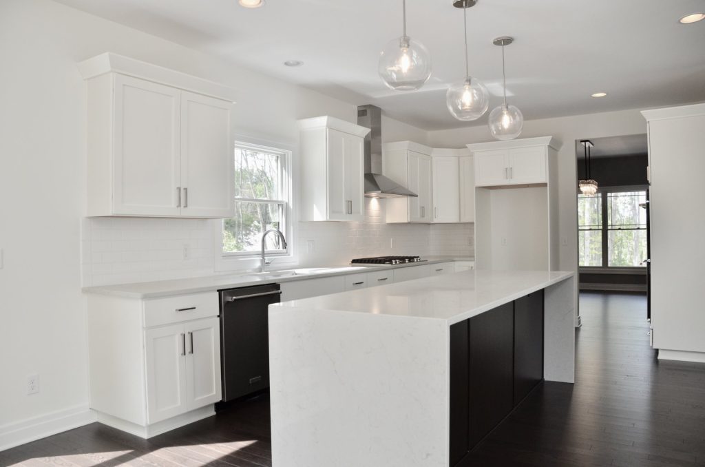 Arbordale-Kitchen-with-White-Cabinetry-Long-Waterfall-Island-Stainless-Hood-and-Pendant-Lighting