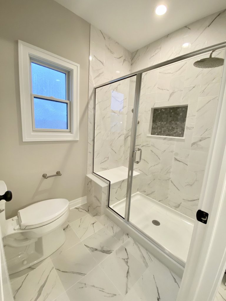 The Portsmouth Primary Bathroom with Glass Shower, Marble-Look Tile, Frosted Window and Built-In Niche