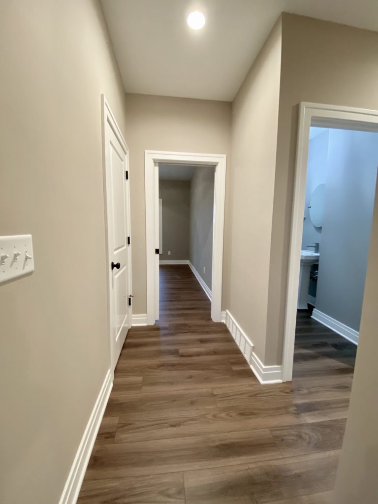 The Portsmouth Hallway with Wood-Look Flooring, White Doors, Neutral Walls and Bathroom Entry