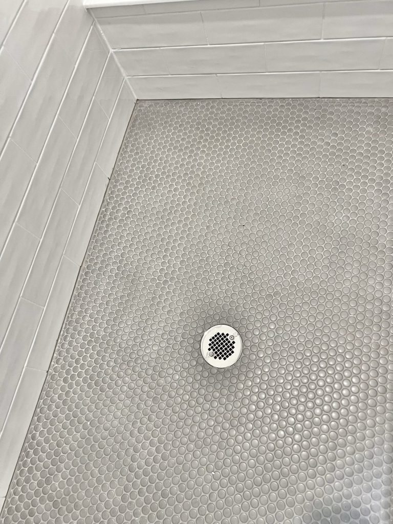 The Cedar Shower Floor Detail with Gray Penny Tile, Center Drain & White Tile Walls
