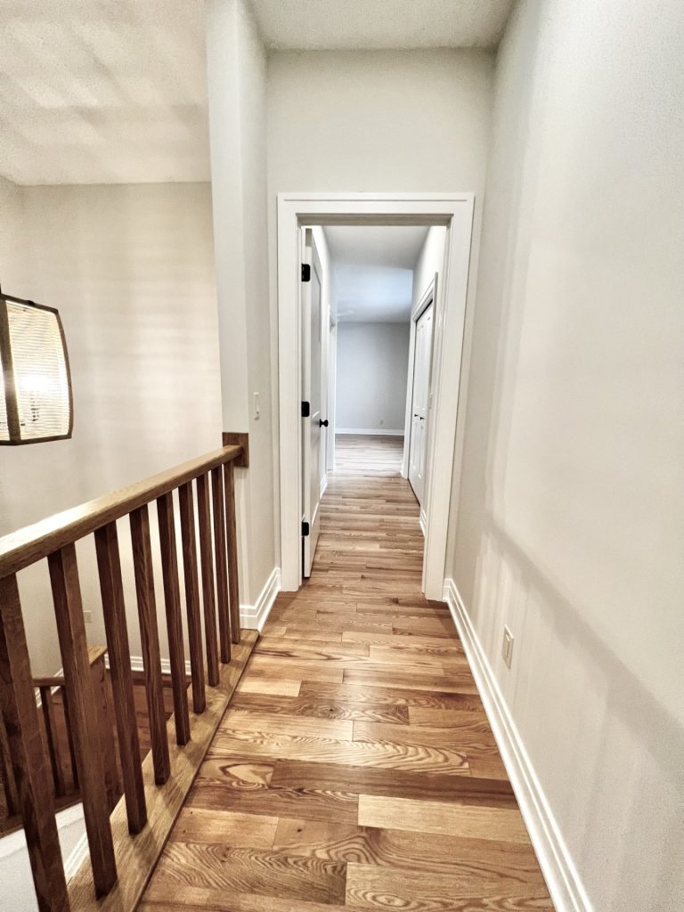 The Cedar Hallway with Hardwood Flooring, Open Railing, Neutral Walls & Bedroom View