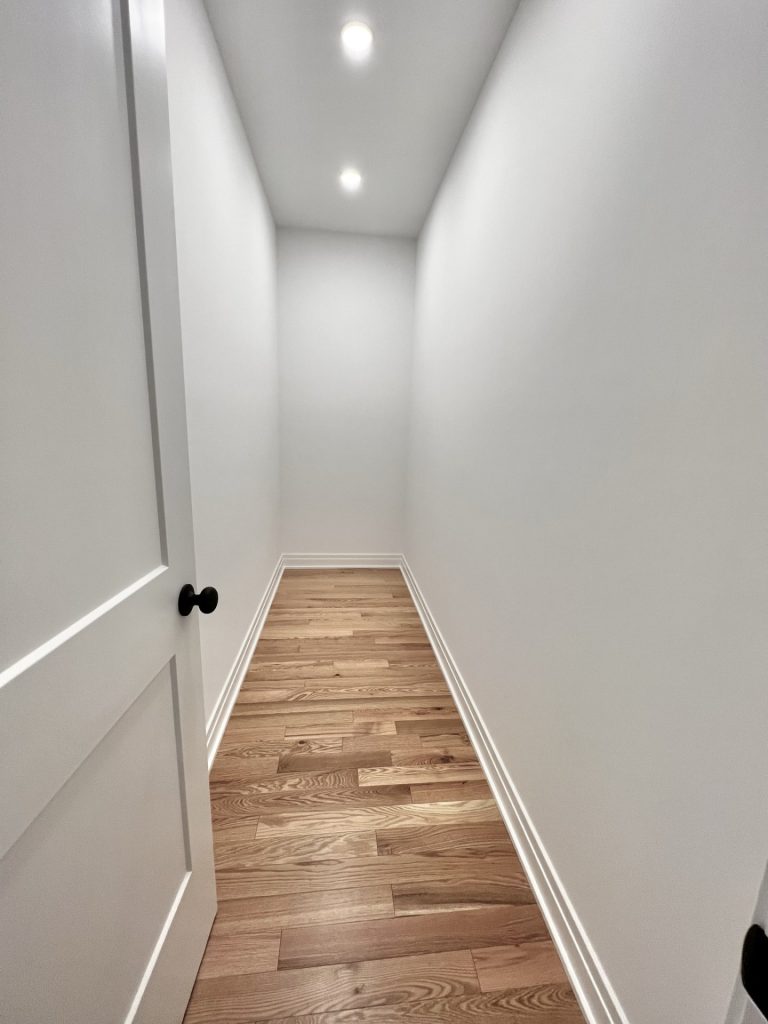 The Cedar Narrow Storage Hall with Recessed Lights, White Walls & Hardwood Flooring