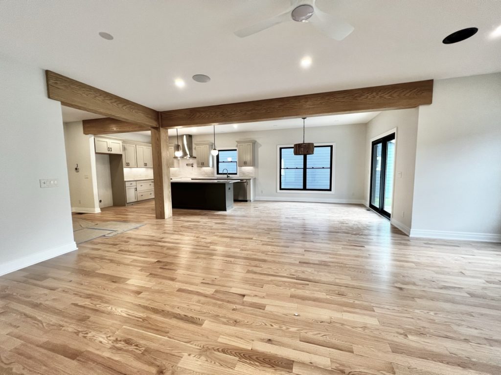The Cedar Open Great Room and Kitchen with Sliding Glass Doors, Wood Beams, Large Island & Hardwood Flooring