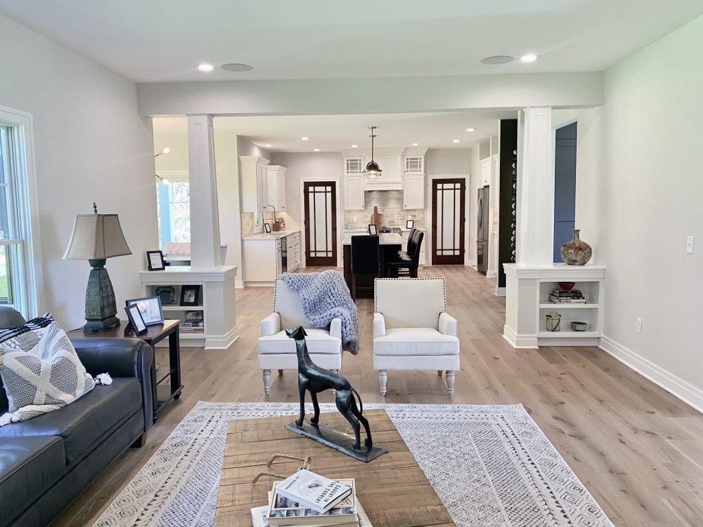 The Ruskin 2.0 Great Room with Built-In Shelving, Accent Columns, Wood-Look Flooring & Kitchen View