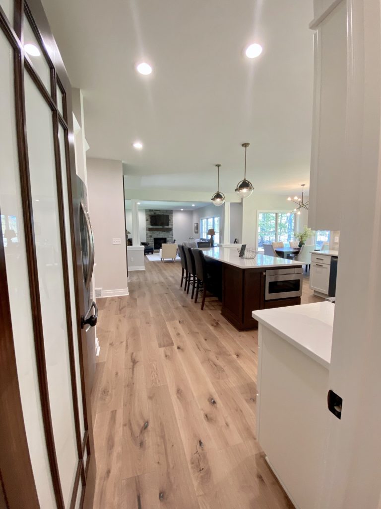 The Ruskin 2.0 Pantry View to Kitchen and Dining Area with Large Island, Picture Window & Wood-Look Flooring