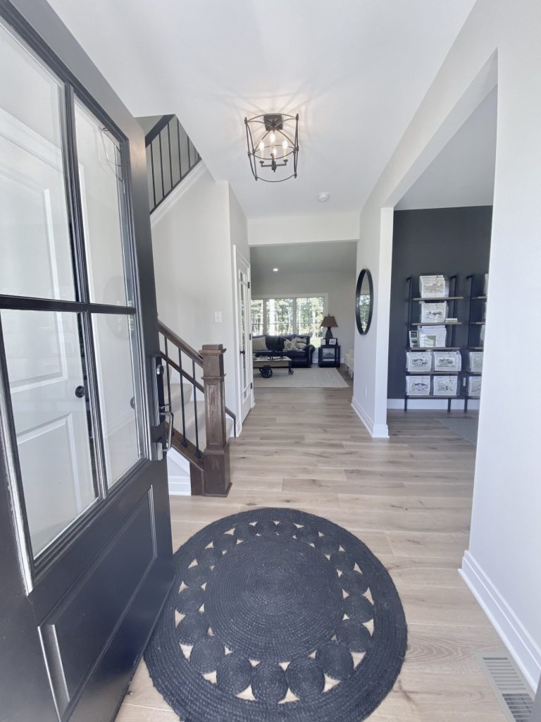 The Ruskin 2.0 Front Entry Hall with Wood-Look Flooring, Dark Stair Rail, Neutral Walls & Great Room View