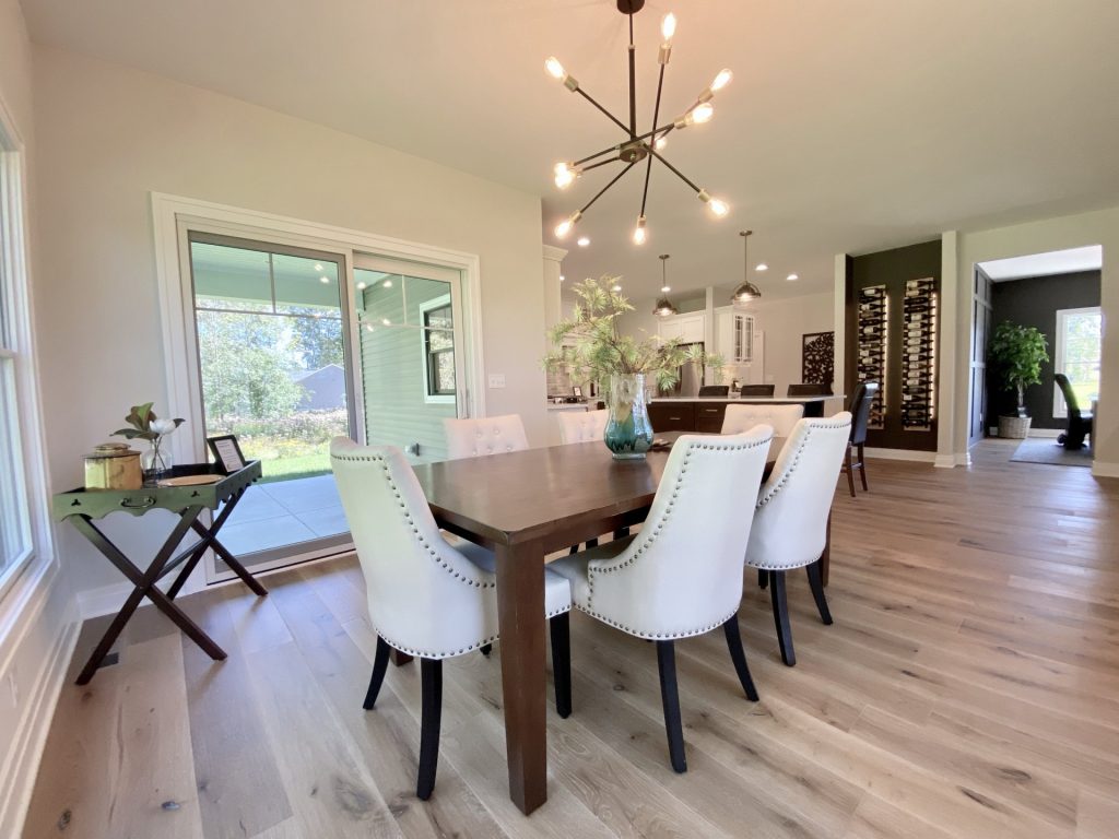 The Ruskin 2.0 Dining Area with Sliding Glass Door, Kitchen View, Modern Chandelier & Wood-Look Flooring