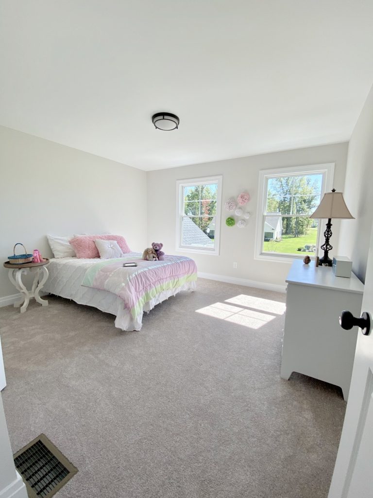 The Ruskin 2.0 Secondary Bedroom with Neutral Carpet, Two Windows, Pastel Bedding & White Dresser