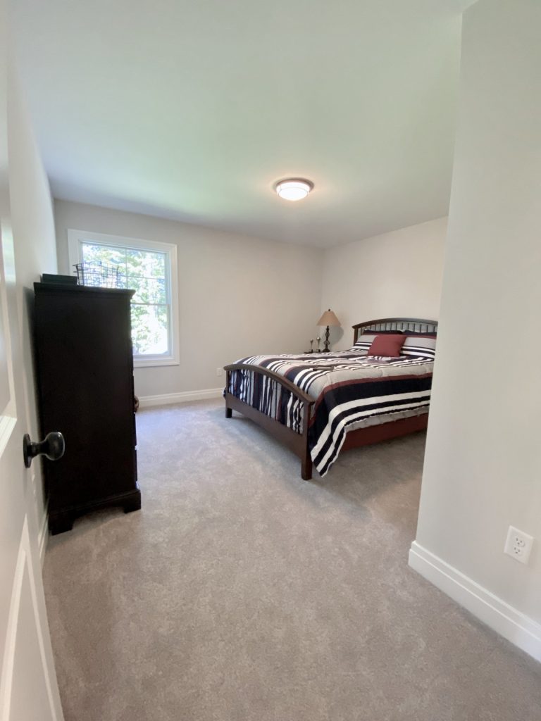 The Ruskin 2.0 Secondary Bedroom with Neutral Carpet, Window, Dark Wood Bed, Dark Dresser & Single Window