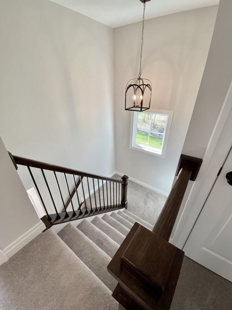 The Ruskin 2.0 Stair Overlook with Hanging Lantern, Dark Railings, Carpeted Stairs & Window Light