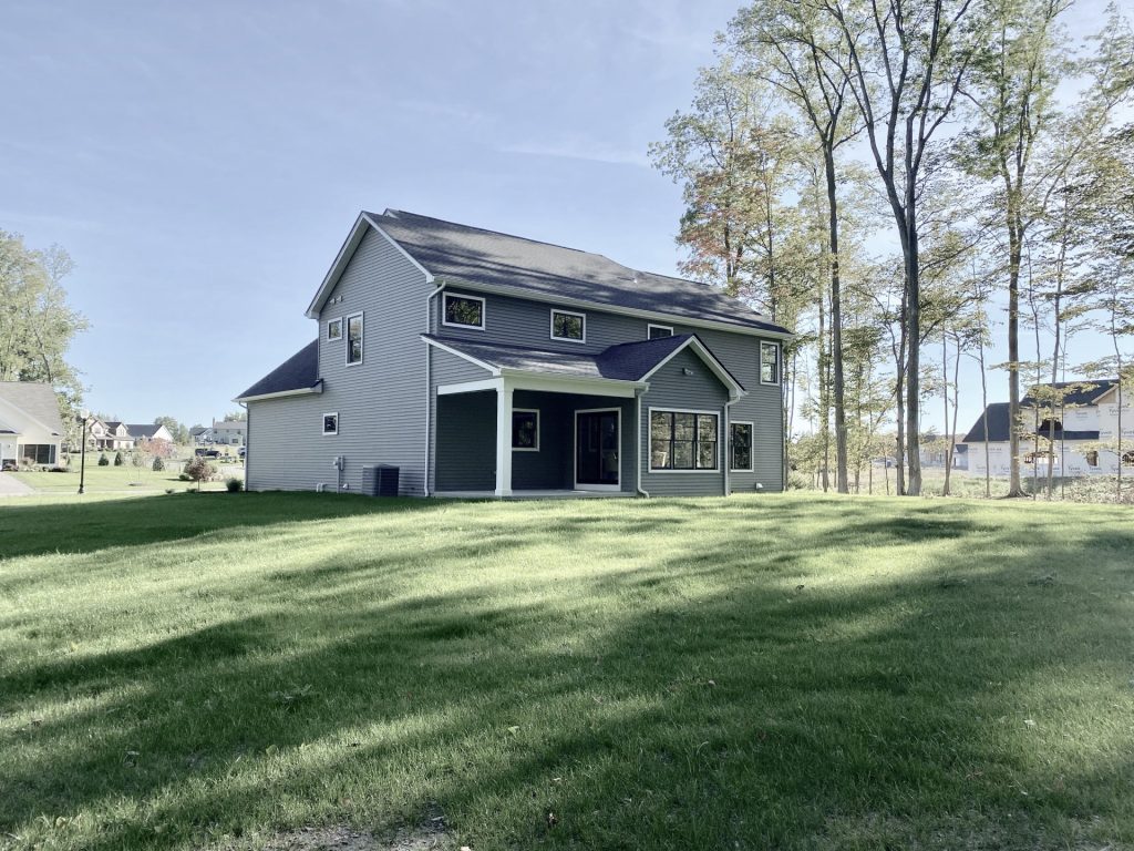 The Ruskin 2.0 Rear Exterior with Covered Porch, Gray Siding, Black Windows & Backyard Lawn