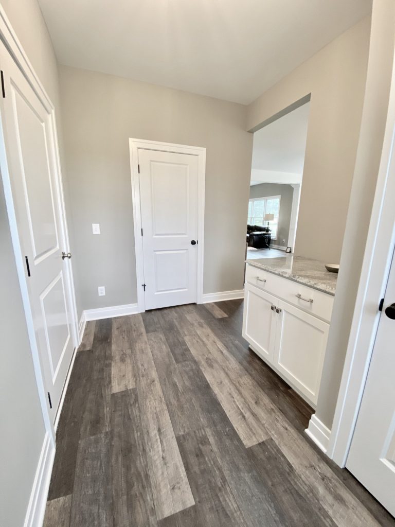 The Willow Mudroom with White Doors, Cabinetry, Dark Wood-Look Flooring and Doorway