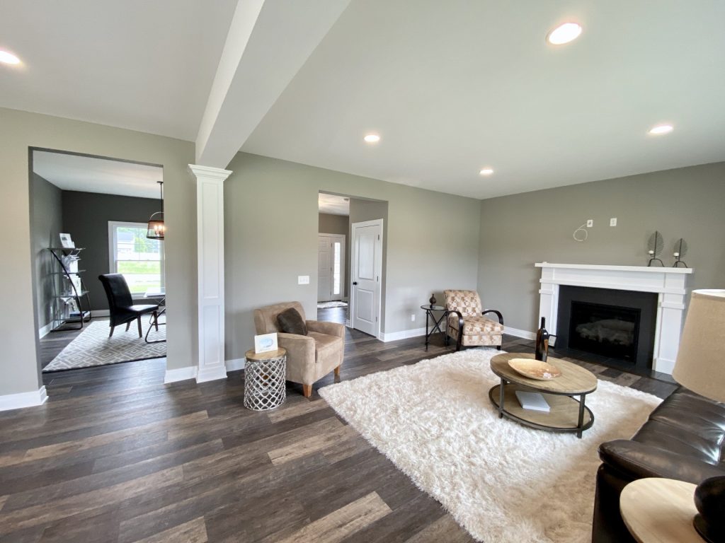 The Weston Great Room with White Mantel Fireplace, Dining Room View, Gray Walls & Wood-Look Flooring
