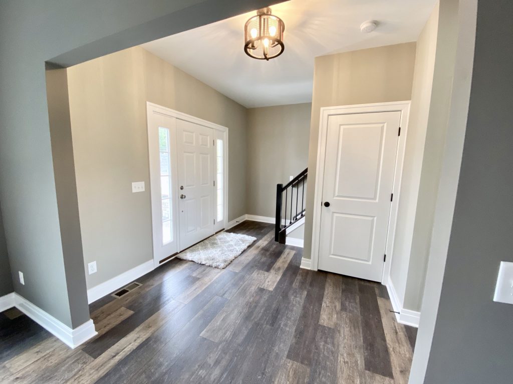 The Weston Front Entry Hall with White Front Door, Closet Door, Wood-Look Flooring & Staircase View