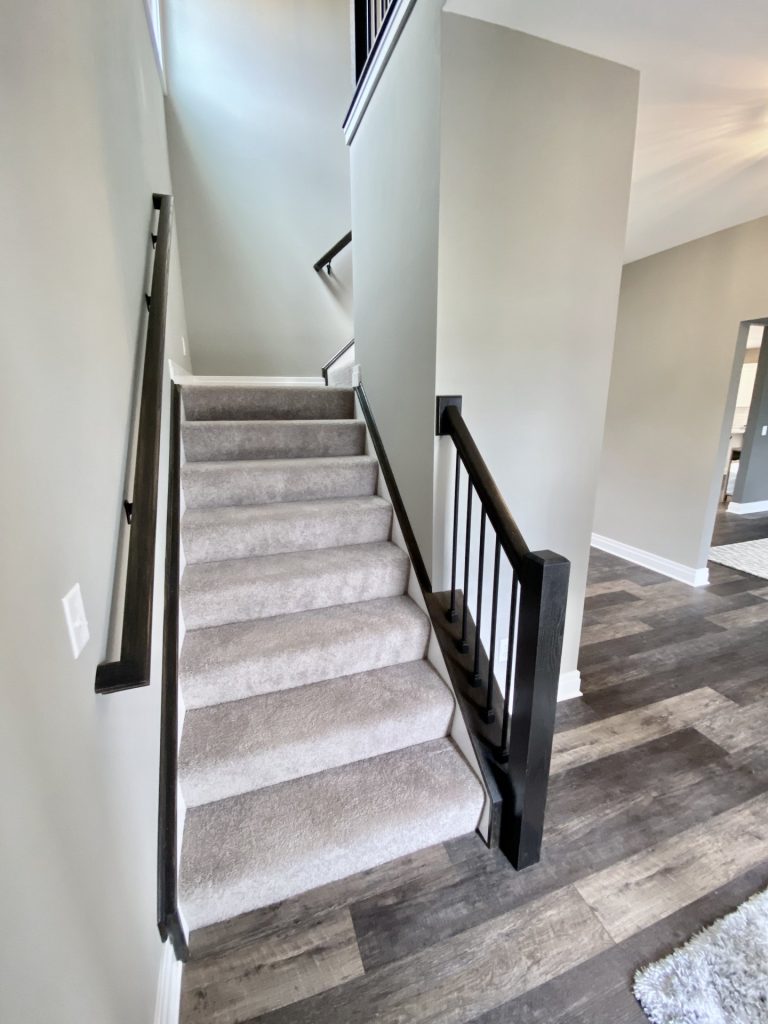 The Weston Staircase with Carpeted Steps, Black Balusters, Dark Handrail & Wood-Look Flooring
