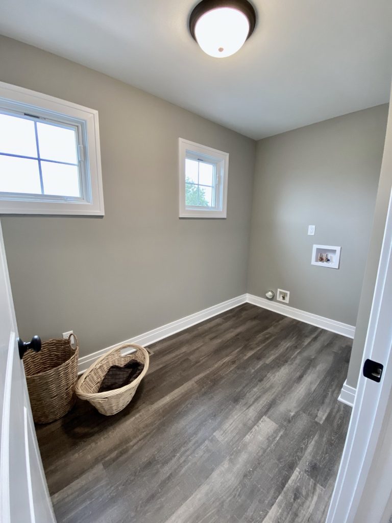 The Weston Laundry Room with Utility Hookups, Gray Walls, Small Windows & Wood-Look Flooring
