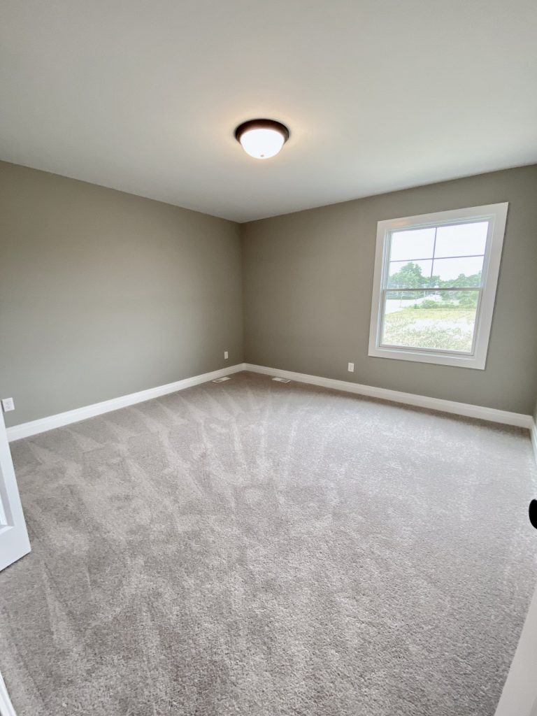 he Weston Secondary Bedroom with Neutral Carpet, Large Window, Olive-Gray Walls & White Trim