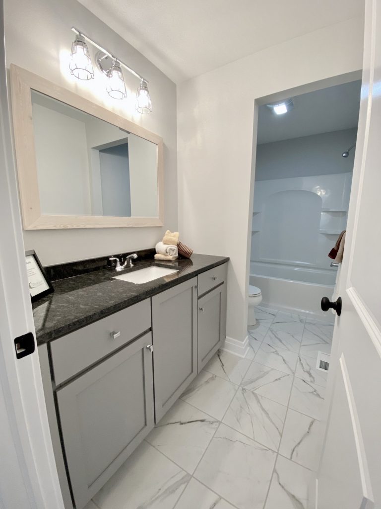 The Weston Full Bathroom with Gray Vanity, Large Mirror, Marble-Look Tile Floor & Tub-Shower Combo View