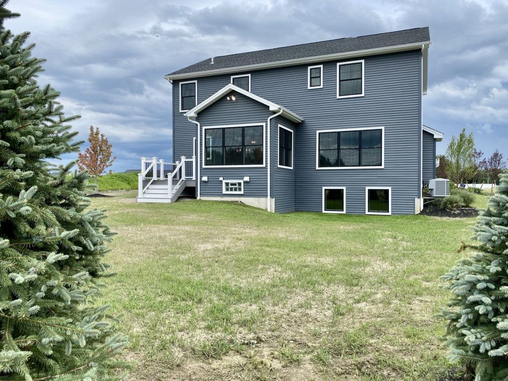 The Weston Rear Exterior with Dark Blue-Gray Siding, Large Windows, White Trim & Backyard View