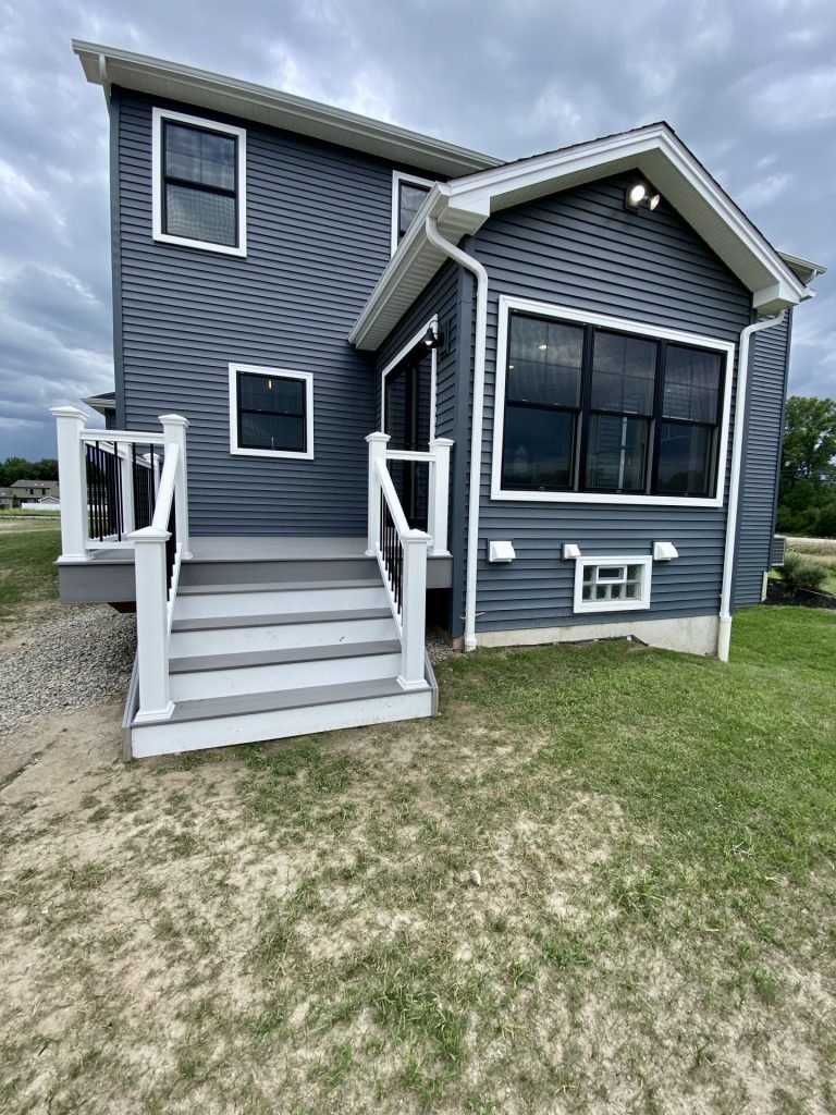 The Weston Rear Exterior Angle with Optional Bump Out, Dark Blue Siding, White Trim & Black-Framed Windows