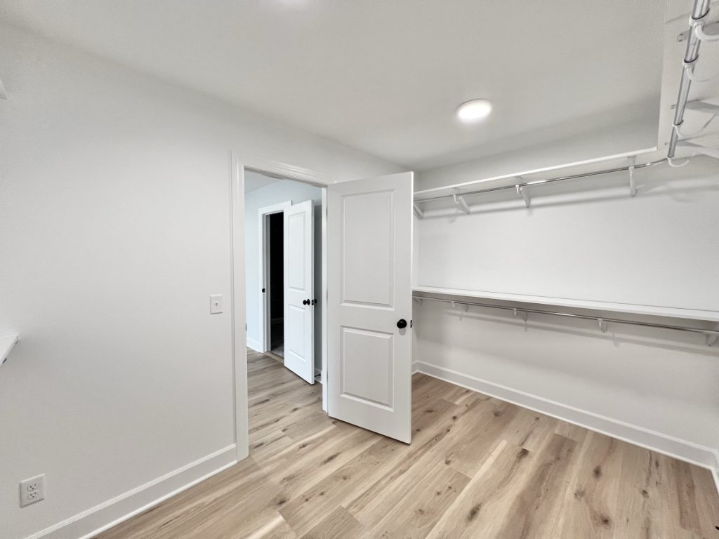 The Willow Walk-In Closet with Open Doorway, Wraparound Shelving, White Walls & Wood-Look Flooring