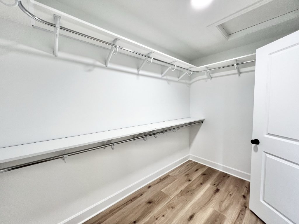 The Willow Walk-in Closet in Light Colors with with Wrap Around Shelving, Attic Access and Wood Flooring