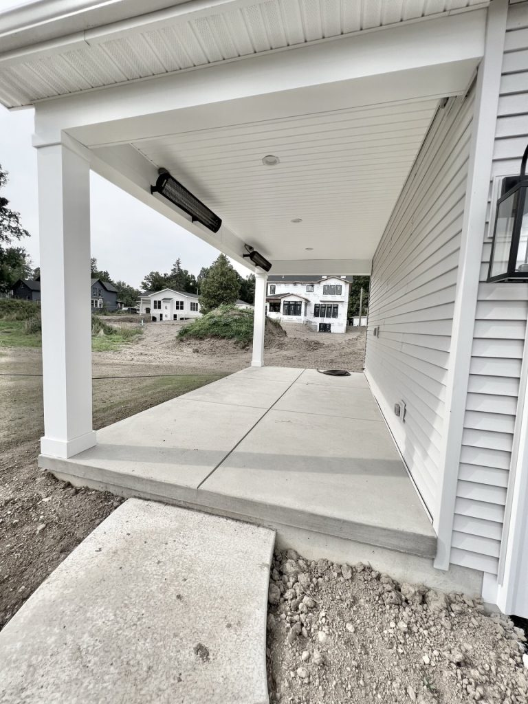 The Willow Covered Rear Porch with Concrete Patio, White Columns, Light Gray Siding & Backyard View