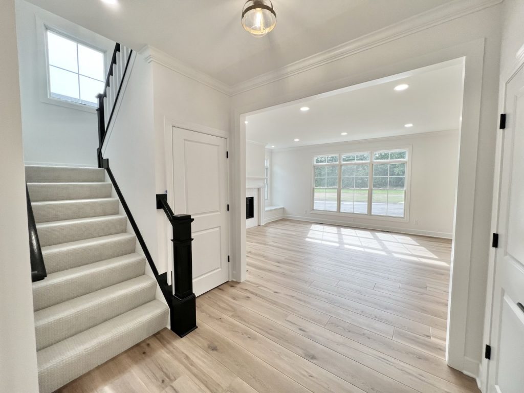 The Willow Hallway to Great Room with Staircase, Large Window, Wood-Look Flooring & Fireplace View