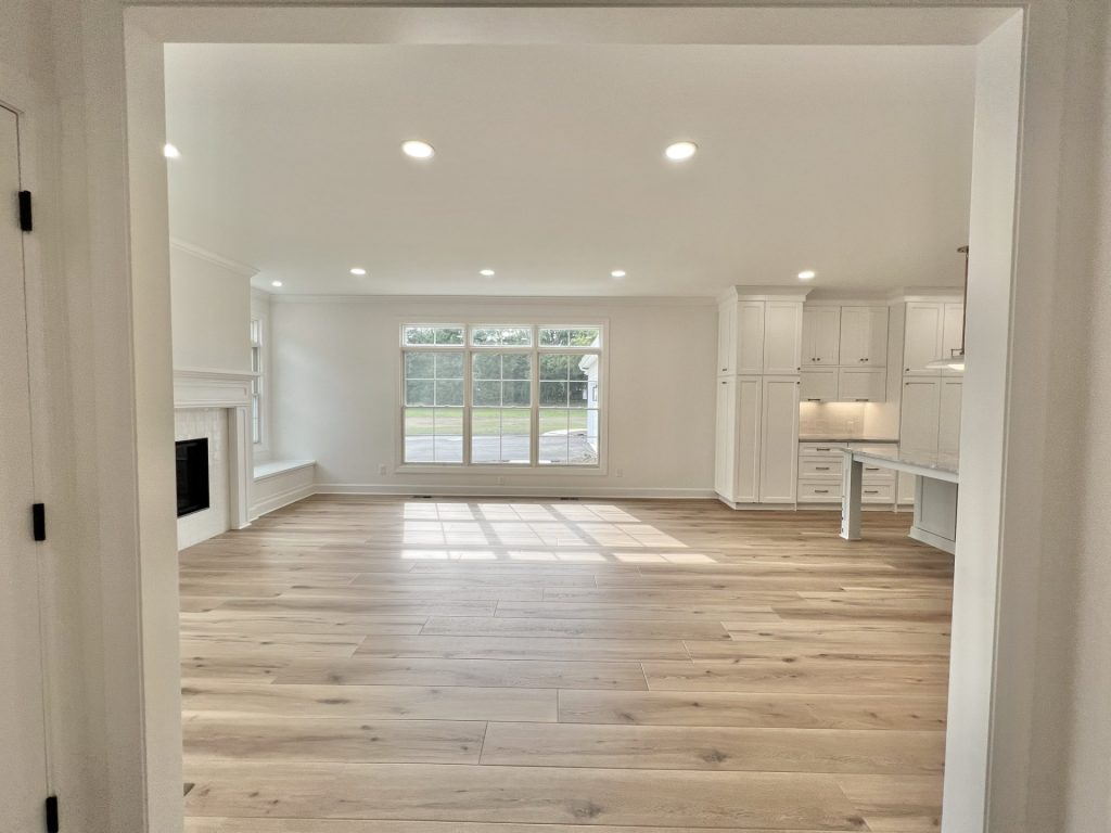 The Willow Open Great Room and Kitchen with Large Window, Fireplace, White Cabinetry & Wood-Look Flooring