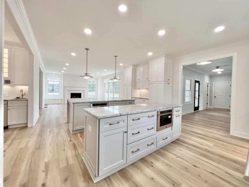The Willow Kitchen Islands with White Cabinetry, Marble Countertops, Pendant Lighting and Front Entry and Great Room View