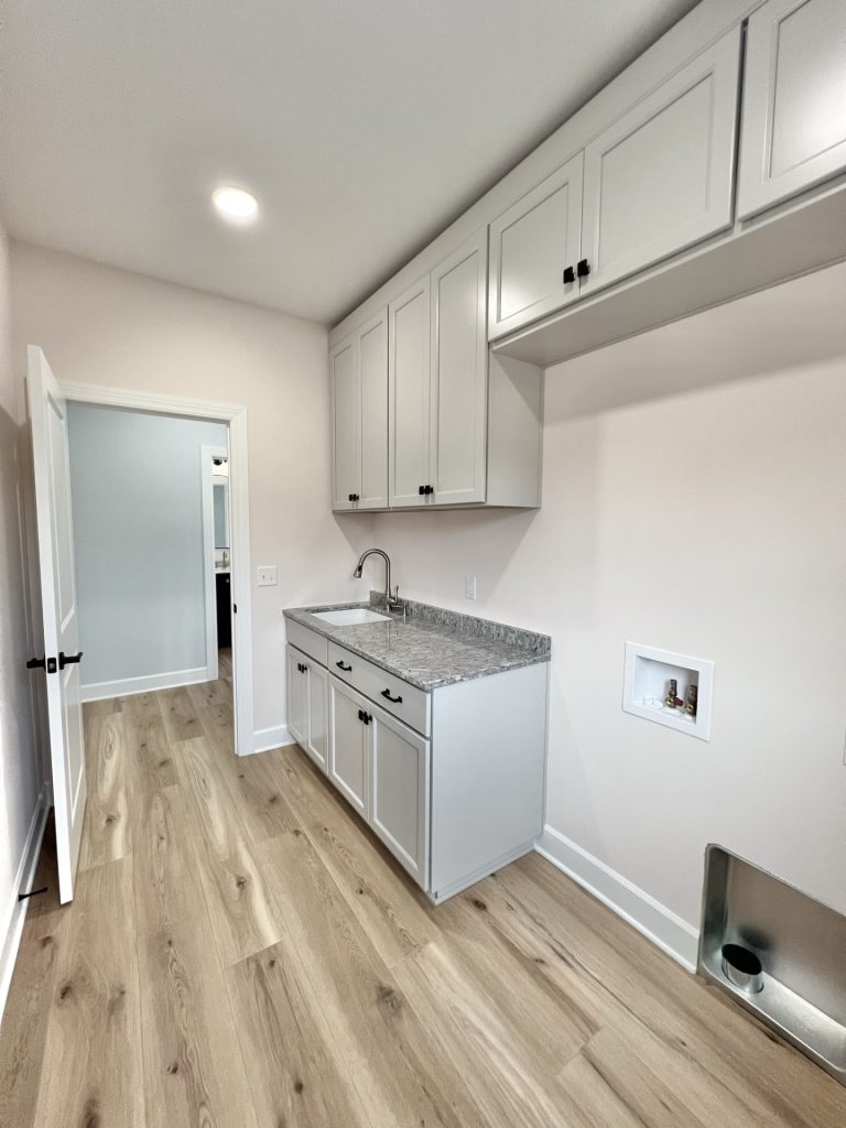 The Willow Laundry Room Sink with Gray Granite Countertop, Cabinetry and Hookups with Wood Style Flooring