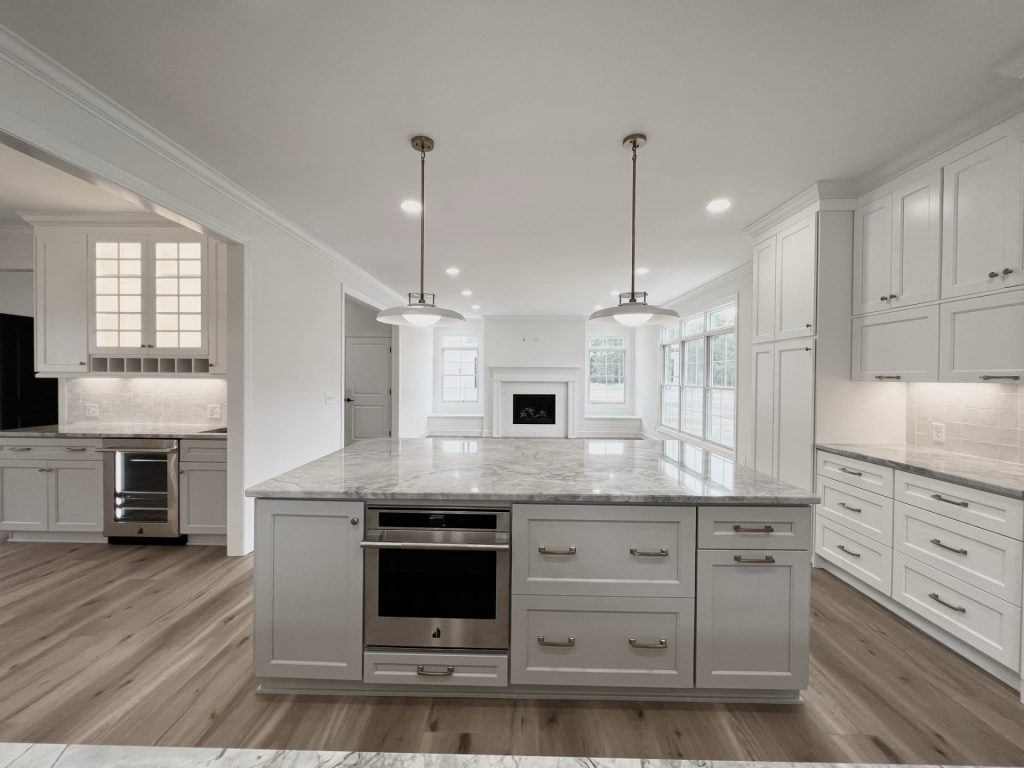 Kitchen with Oversized Island, Marble Countertops, White Cabinetry, an Extra Cooking Station and a Fireplace View