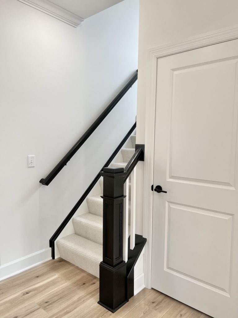 The Willow White, Carpeted Staircase with Dark Railing and White Door