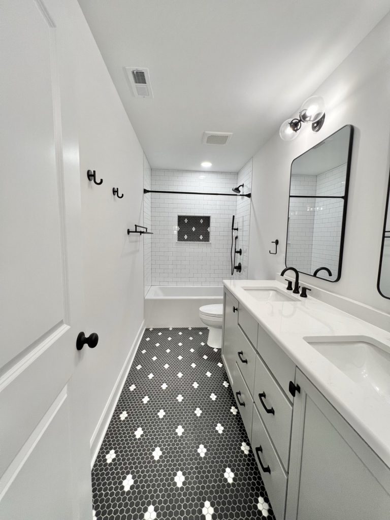 The Willow Bathroom in Black and White with Double Vanities, a Shower-Tub Combo with Mosaic Niche and Dark Mosaic Flooring