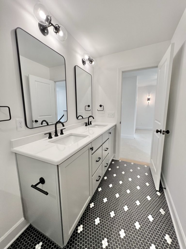 The Willow Bathroom with Double Vanity with White Cabinetry, Dual Mirrors, Dark Mosaic Tile Floor