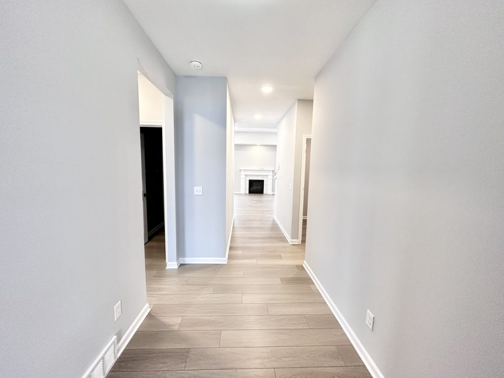 The Kendall Front Hallway with Wood-Look Flooring, Gray Walls, Recessed Lighting & Fireplace View