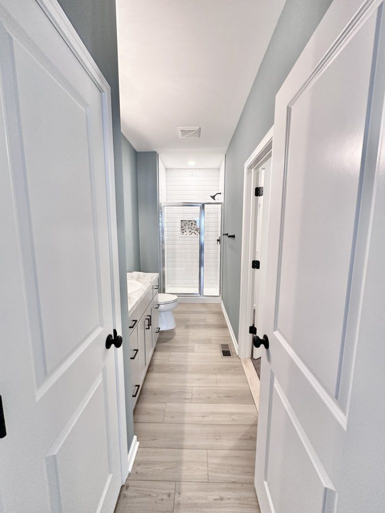 The Kendall Primary Bathroom with Gray Vanity, Glass Shower, Tile Flooring & Black Fixtures