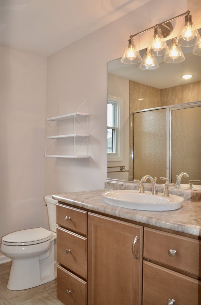 Baybrook-I-Primary-Bathroom-with-Wood-Vanity-Large-Mirror-Glass-Shower-and-Tile-Flooring