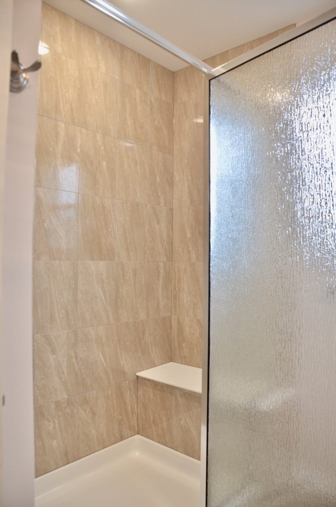 Baybrook-I-Glass-Enclosed-Shower-with-Beige-Tile-Walls-Built-In-Seat-and-Textured-Glass-Door