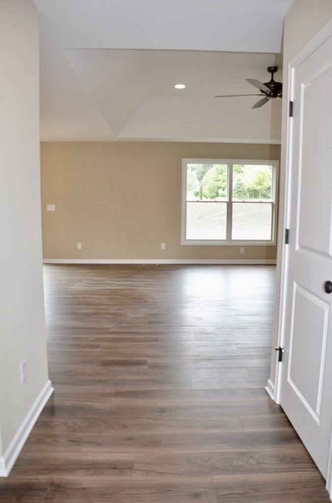 Baybrook-I-Great-Room-Entry-with-Tray-Ceiling-Ceiling-Fan-Large-Window-and-Wood-Look-Flooring