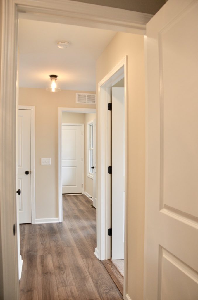 Baybrook-I-Interior-Hallway-with-Wood-Look-Flooring-White-Trim-and-Front-Entry-View
