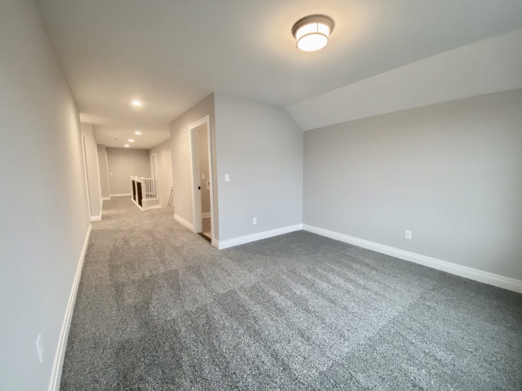 The Cooper II Flex Room with Gray Carpet, Light Walls, Flush-Mount Ceiling Light & Open Hallway View