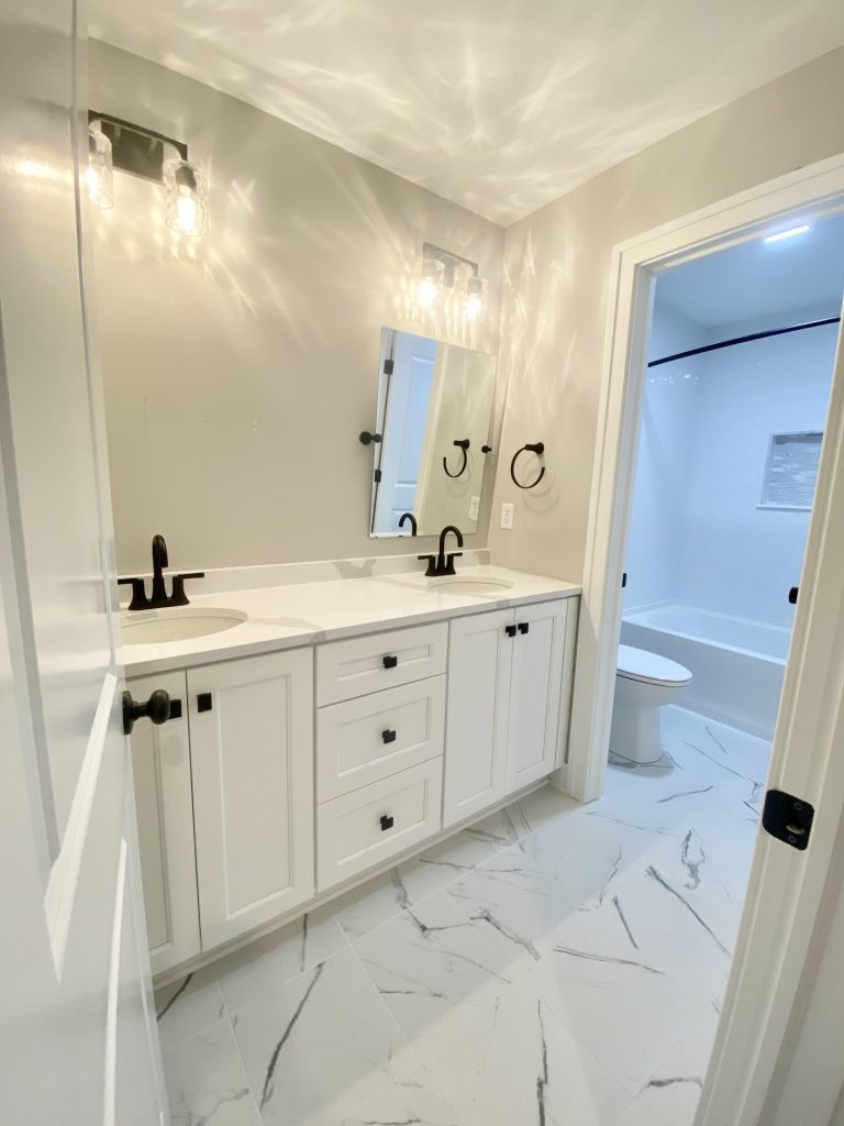 The Cooper II Full Bathroom with Double Vanity, Marble-Look Tile Floor, Black Fixtures & Tub View