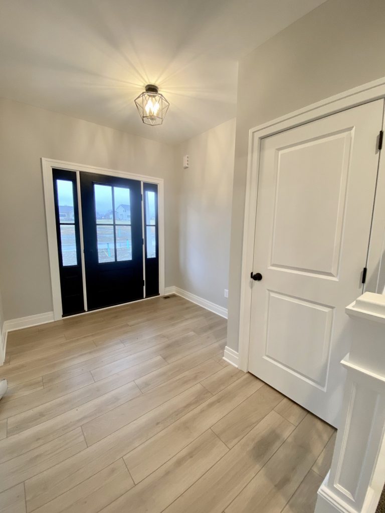 The Cooper II Front Entry with Black Front Door, Wood-Look Flooring, White Trim & Stair Landing