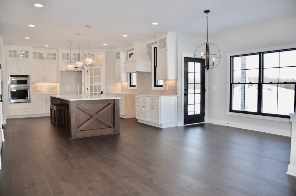 The Stratford II Open Kitchen with Island, Double Wall Ovens, Dining Area & Dark Wood Flooring