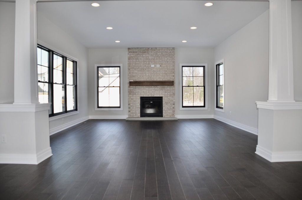 The Stratford II Open Great Room with Fireplace, Columns, Dark Wood Flooring & Open Layout