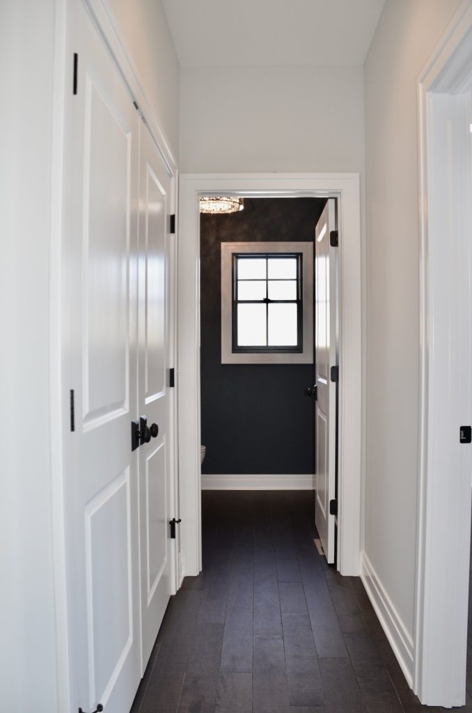 Hallway to Powder Room with Dark Wood Flooring, White Doors, Neutral Walls & Powder Room View