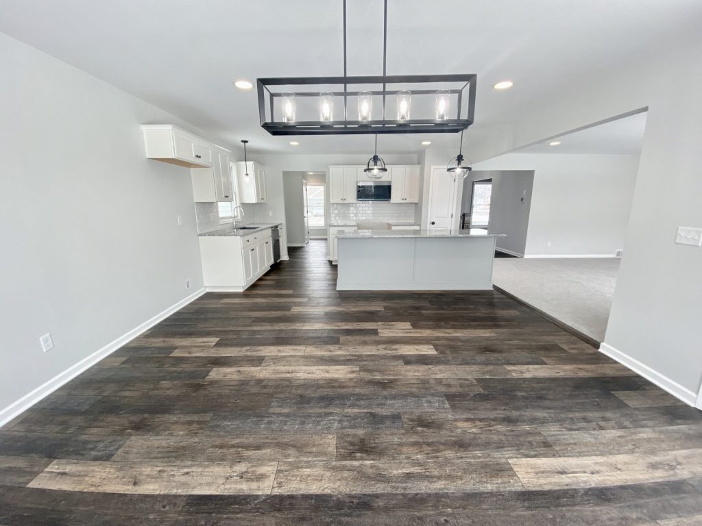 The Cooper I Dinette with Linear Chandelier, Kitchen Island, White Cabinetry & Wood-Look Flooring