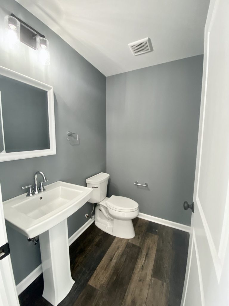 The Cooper I Powder Room with Gray Walls, Pedestal Sink, White Trim & Wood-Look Flooring